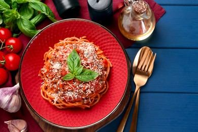 Photo of Delicious pasta bolognese with basil served on blue wooden table, top view