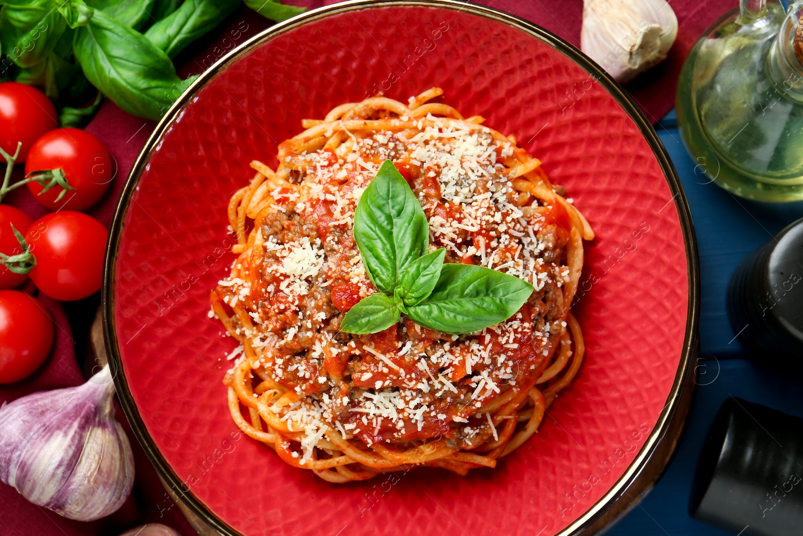 Photo of Delicious pasta bolognese with basil served on blue wooden table, top view