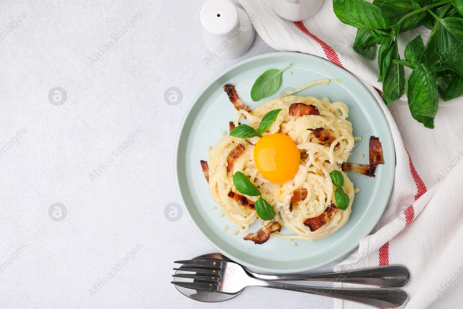 Photo of Delicious pasta Carbonara served on light gray table, flat lay. Space for text