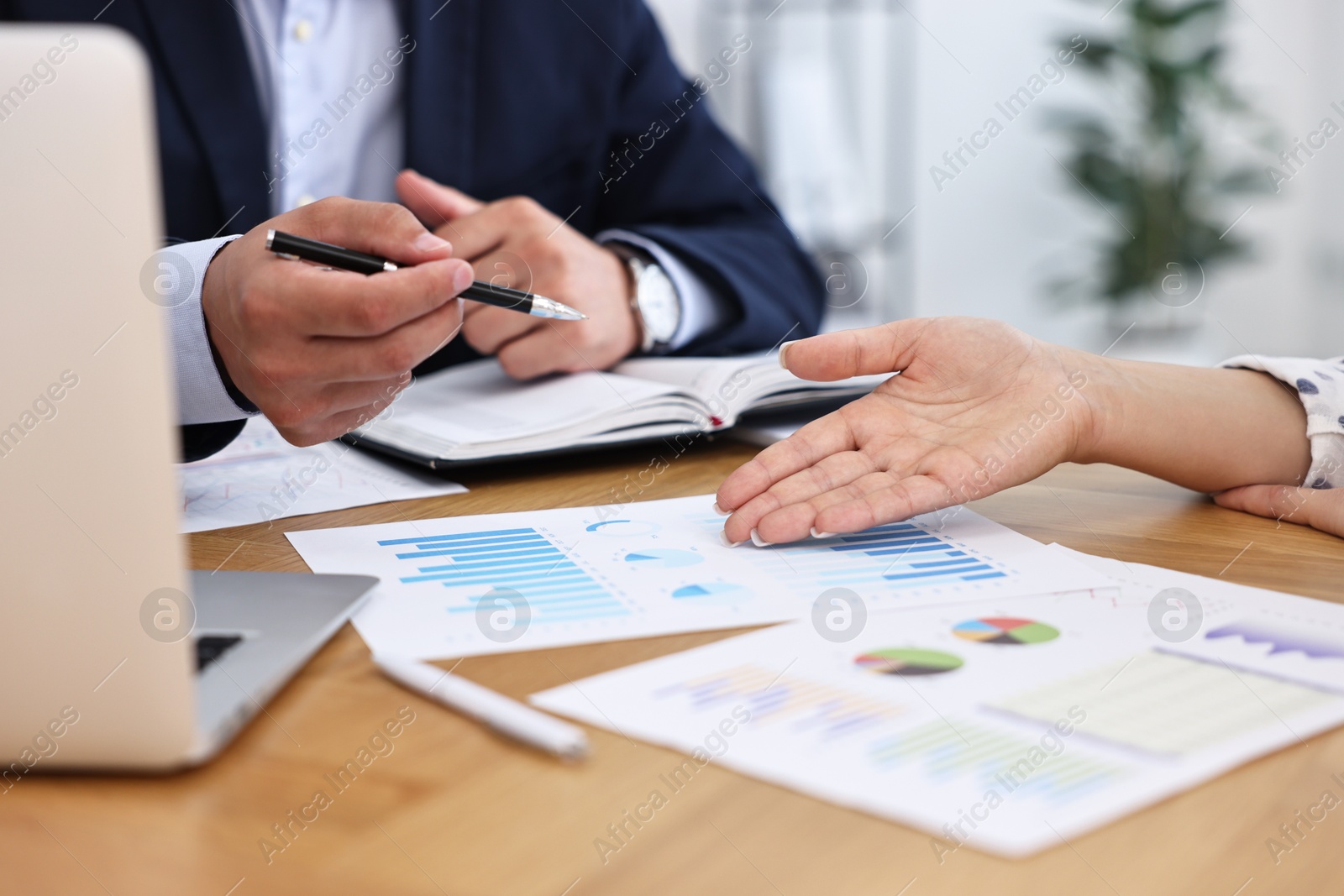 Photo of Banker working with client at wooden table in office, closeup