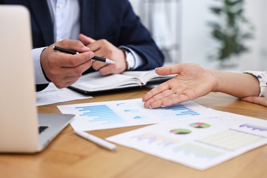 Banker working with client at wooden table in office, closeup