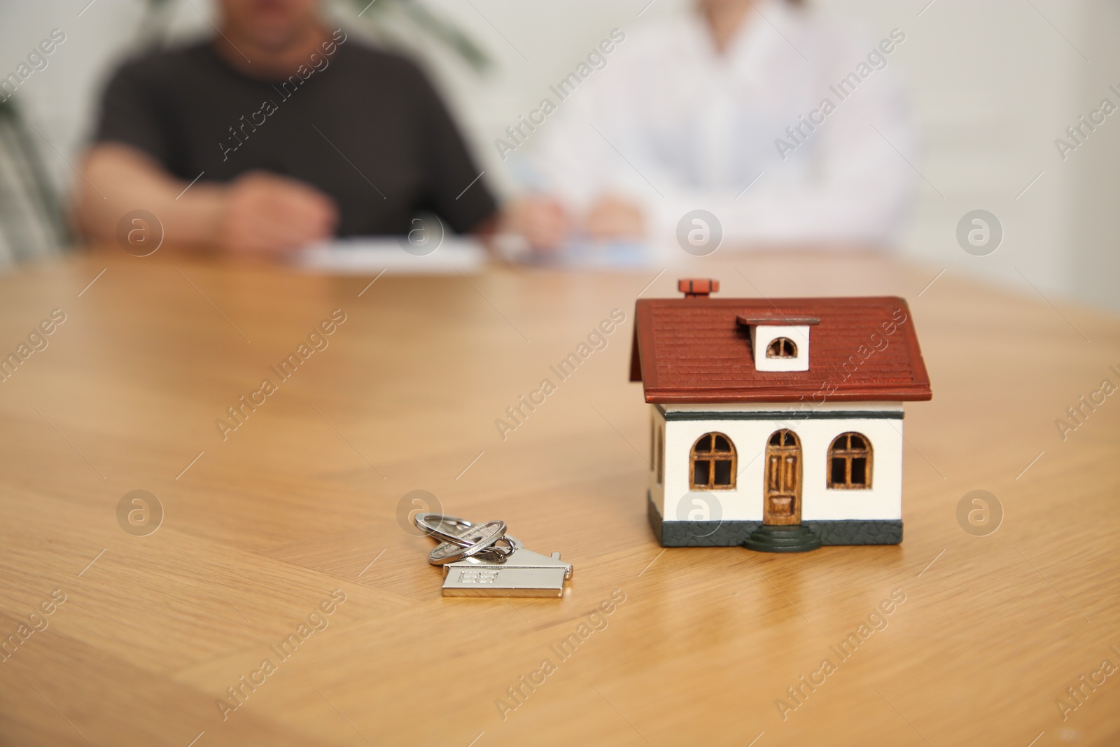 Photo of House model and key on wooden table indoors, selective focus