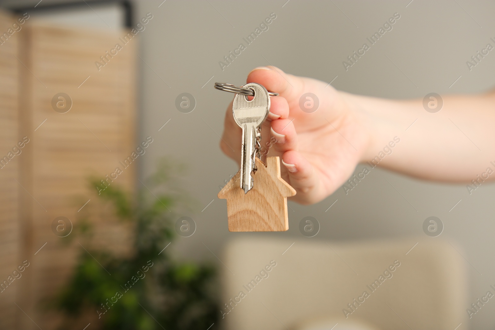 Photo of Woman with wooden house model and key indoors, closeup