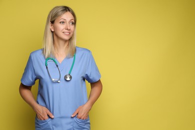 Portrait of nurse in medical uniform with stethoscope on yellow background, space for text