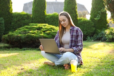 Woman using laptop on green lawn in park