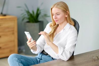 Beautiful woman using smartphone at table in office