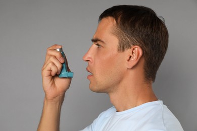 Photo of Man using asthma inhaler on grey background