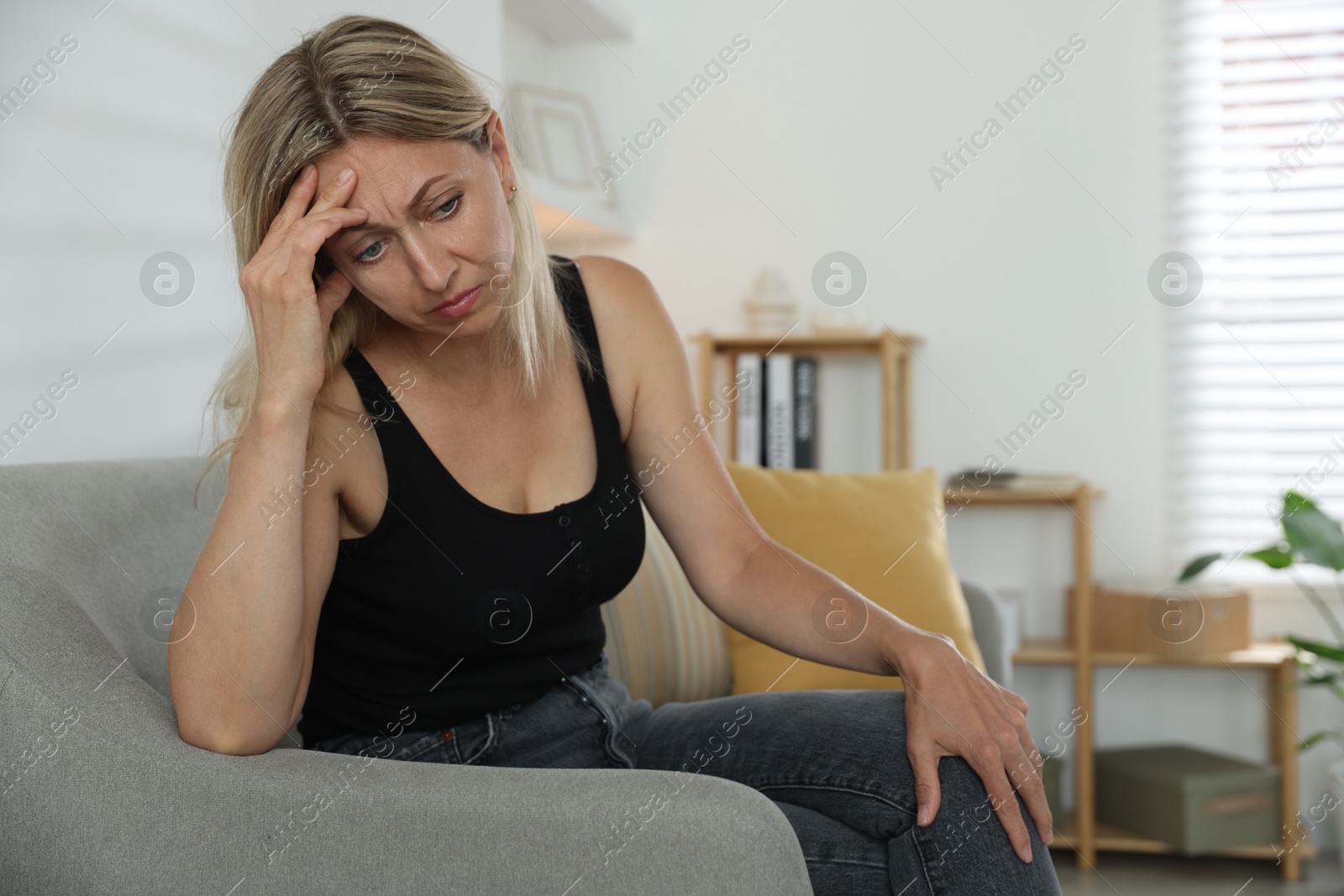 Photo of Menopause. Woman suffering from headache on sofa at home