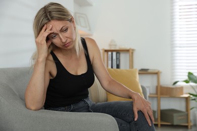 Menopause. Woman suffering from headache on sofa at home