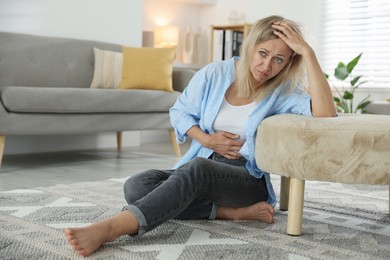 Photo of Menopause. Woman suffering from abdominal pain on floor at home