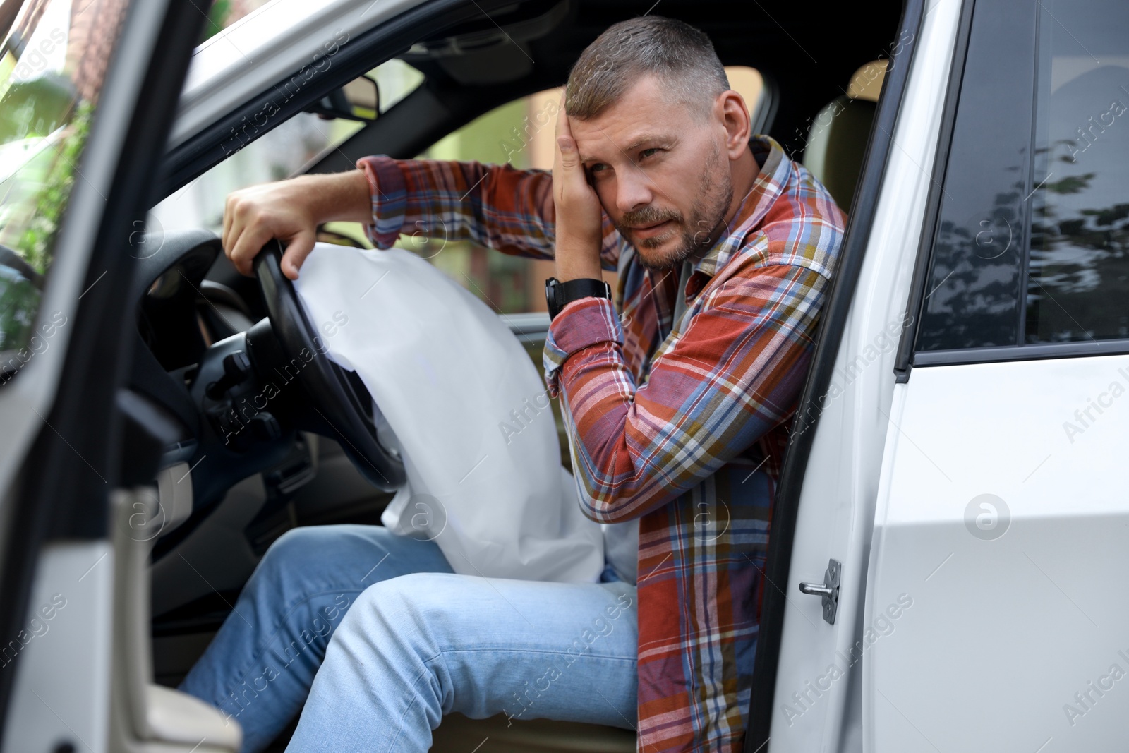 Photo of Injured man near opened airbag in automobile after car accident