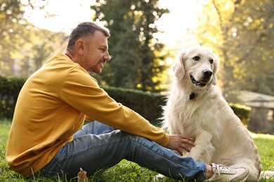 Photo of Smiling man with cute Golden Retriever dog on spring day