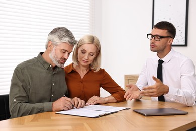 Photo of Pension plan. Couple consulting with insurance agent at table indoors