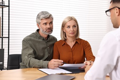 Photo of Pension plan. Couple consulting with insurance agent at table indoors