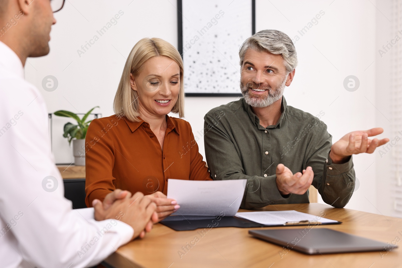 Photo of Pension plan. Couple consulting with insurance agent at table indoors