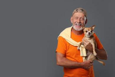 Photo of Portrait of happy senior man with cute Chihuahua dog on grey background. Space for text