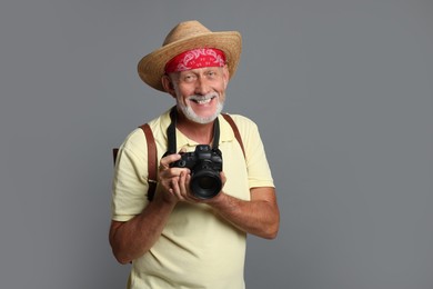 Portrait of happy senior man with camera on grey background