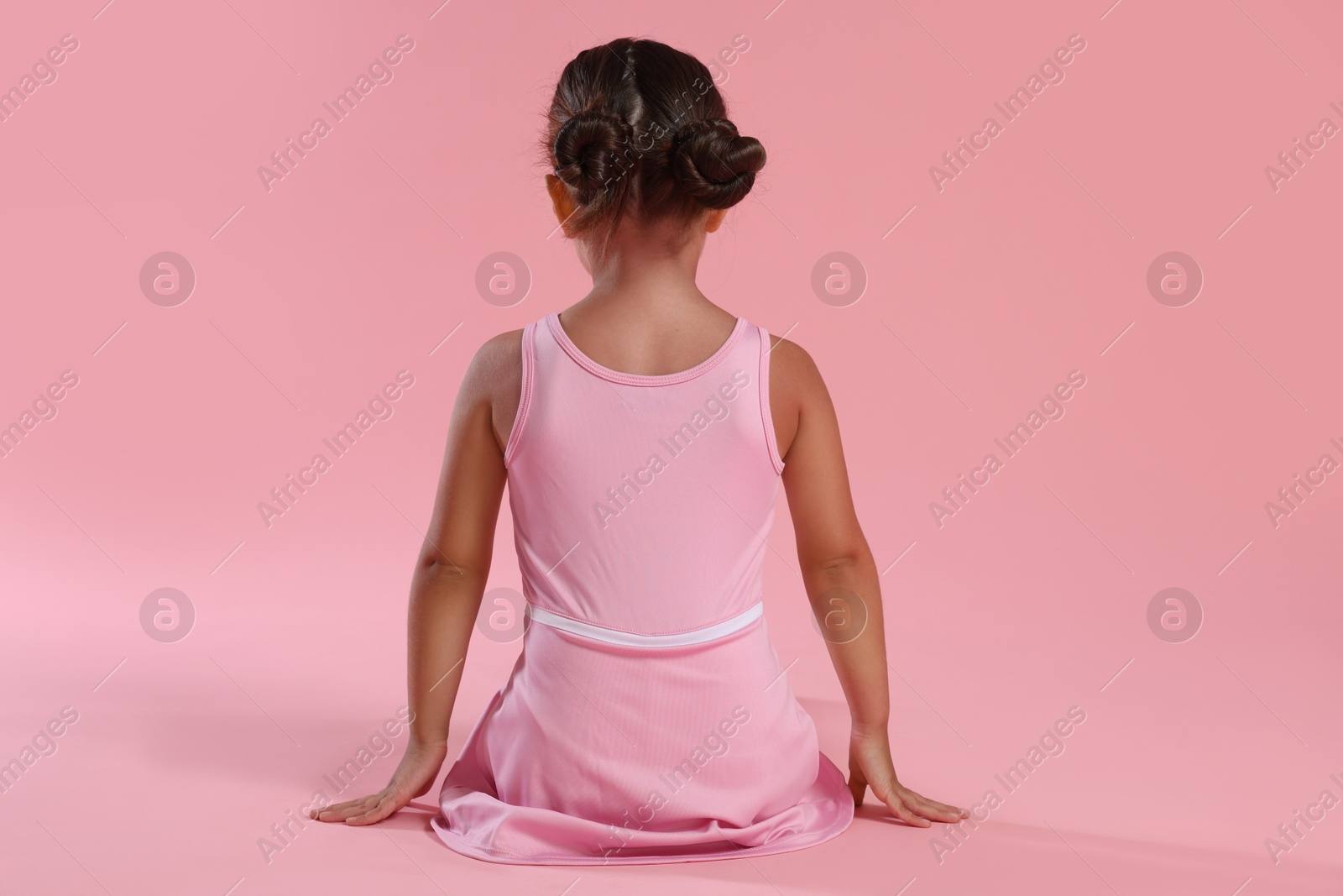 Photo of Little ballerina on pink background, back view