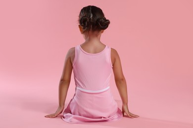 Photo of Little ballerina on pink background, back view