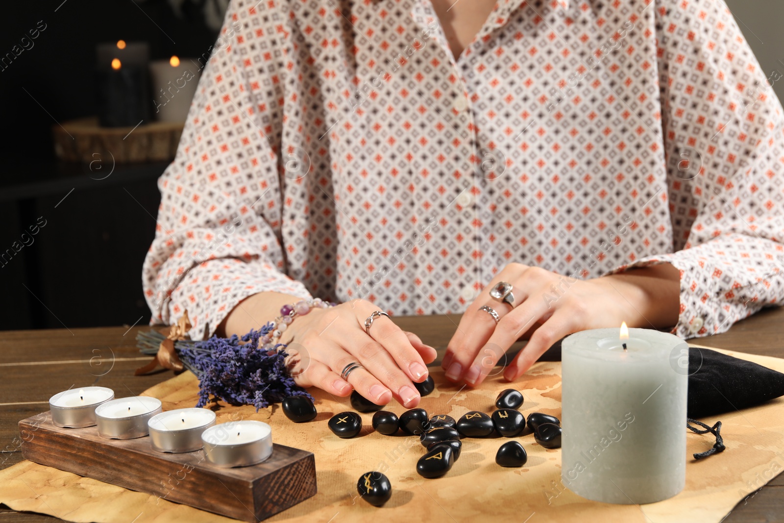 Photo of Woman with black runes at table indoors, closeup