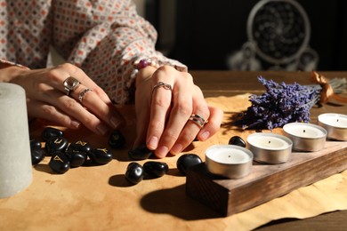 Woman with black runes at table indoors, closeup