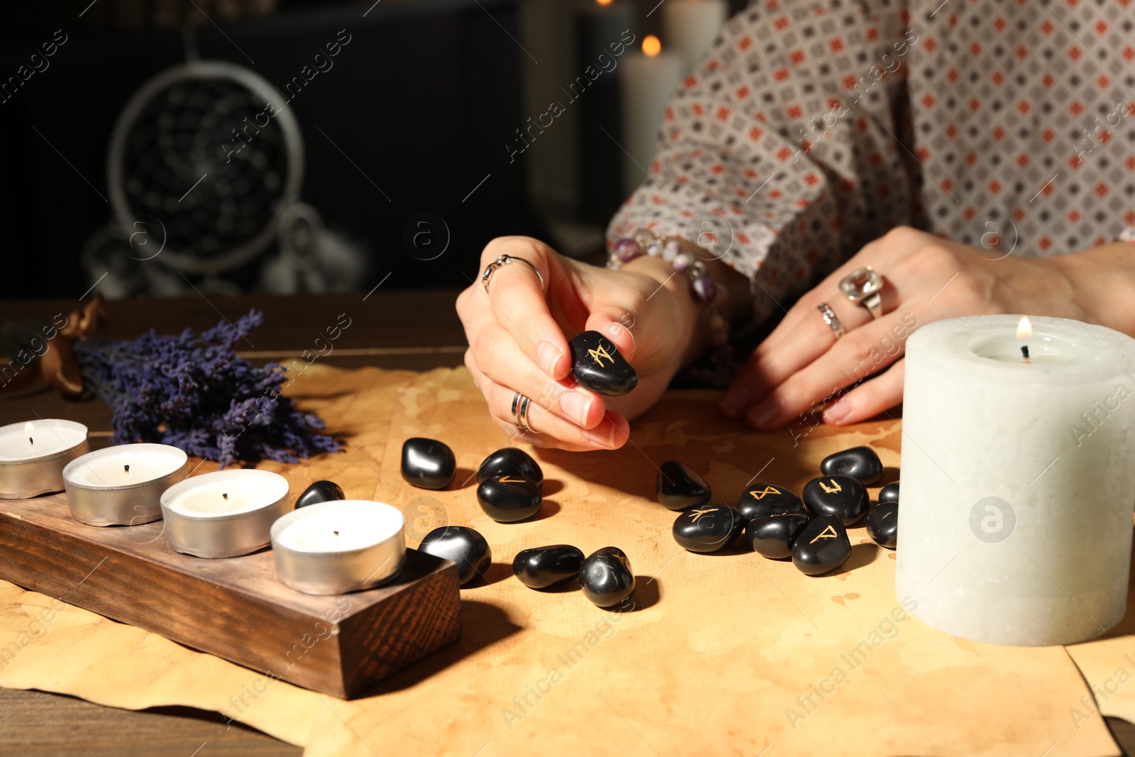 Photo of Woman with black runes at table indoors, closeup