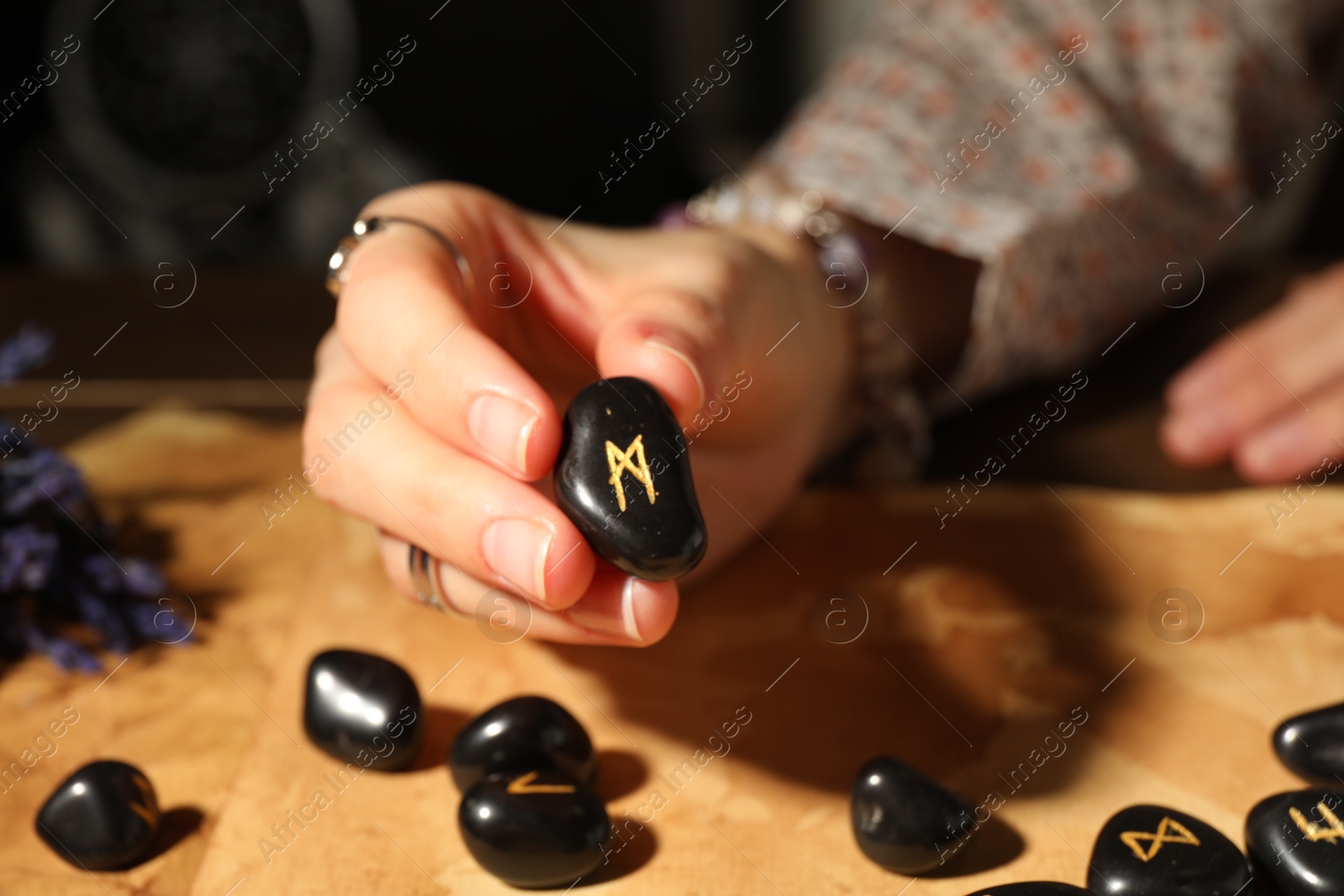 Photo of Woman with black rune Mannaz at table indoors, closeup