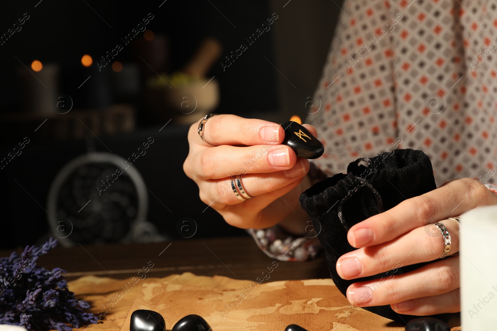 Photo of Woman with black rune Mannaz at table indoors, closeup