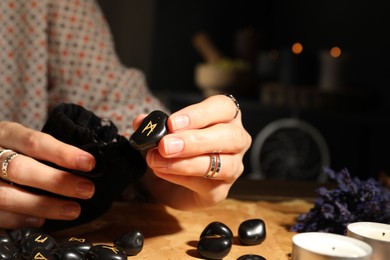 Photo of Woman with black rune Mannaz at table indoors, closeup