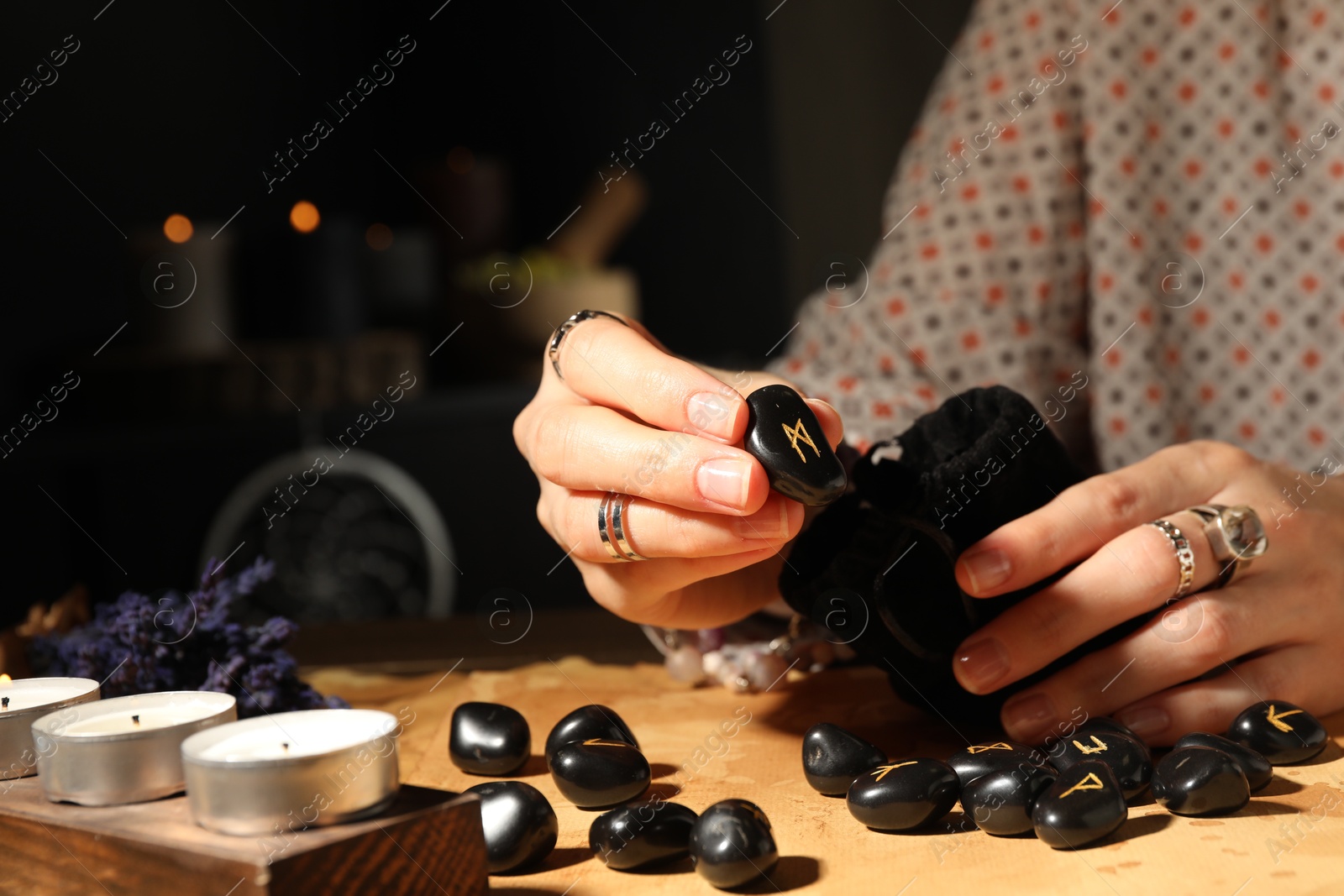 Photo of Woman with black rune Mannaz at table indoors, closeup