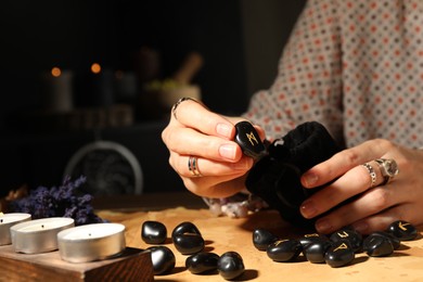 Photo of Woman with black rune Mannaz at table indoors, closeup