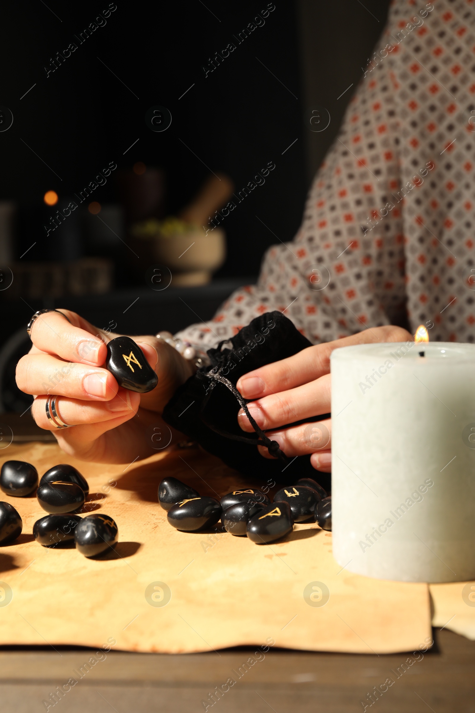 Photo of Woman with black runes at table indoors, closeup