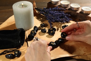 Photo of Woman with black rune Raido at table indoors, closeup