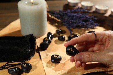 Photo of Woman with black rune Raido at table indoors, closeup