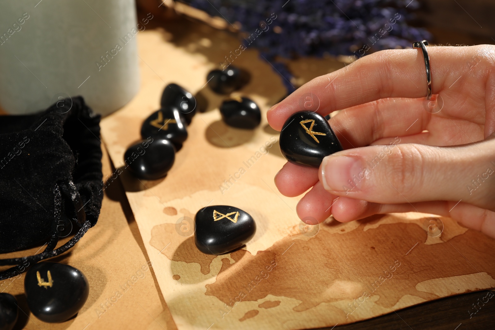 Photo of Woman with black rune Raido at table indoors, closeup