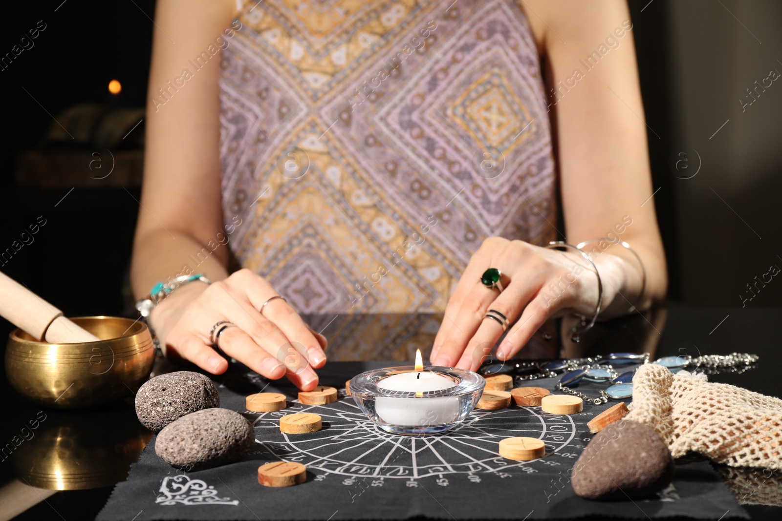 Photo of Woman with wooden runes at divination mat indoors, closeup