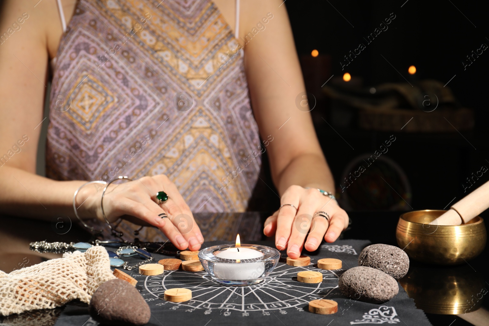 Photo of Woman with wooden runes at divination mat indoors, closeup