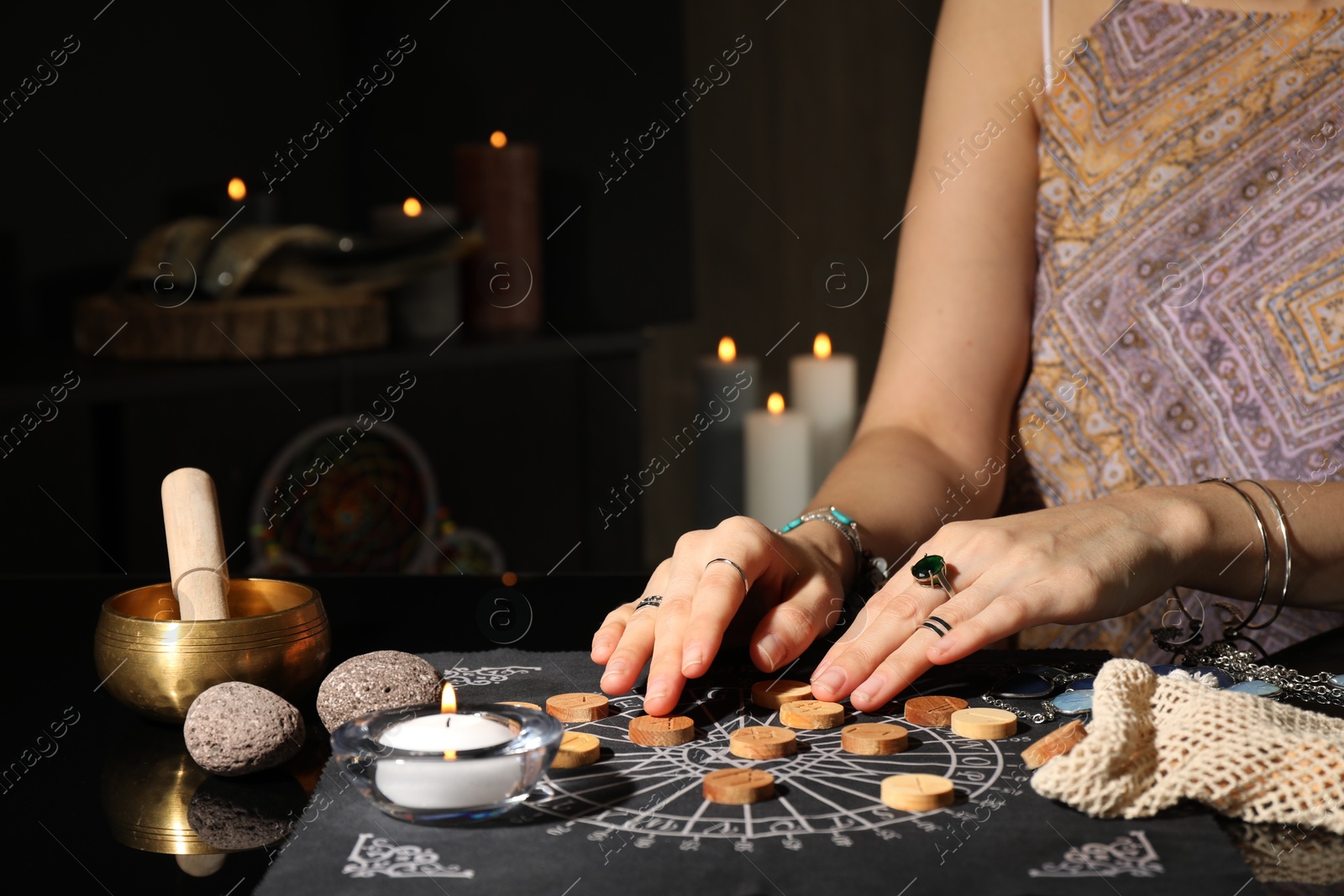 Photo of Woman with wooden runes at divination mat indoors, closeup