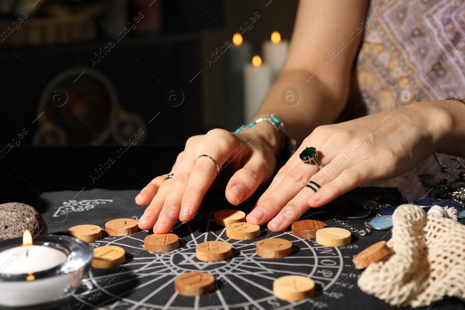 Photo of Woman with wooden runes at divination mat indoors, closeup