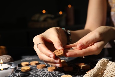 Photo of Woman with wooden rune Mannaz at divination mat indoors, closeup