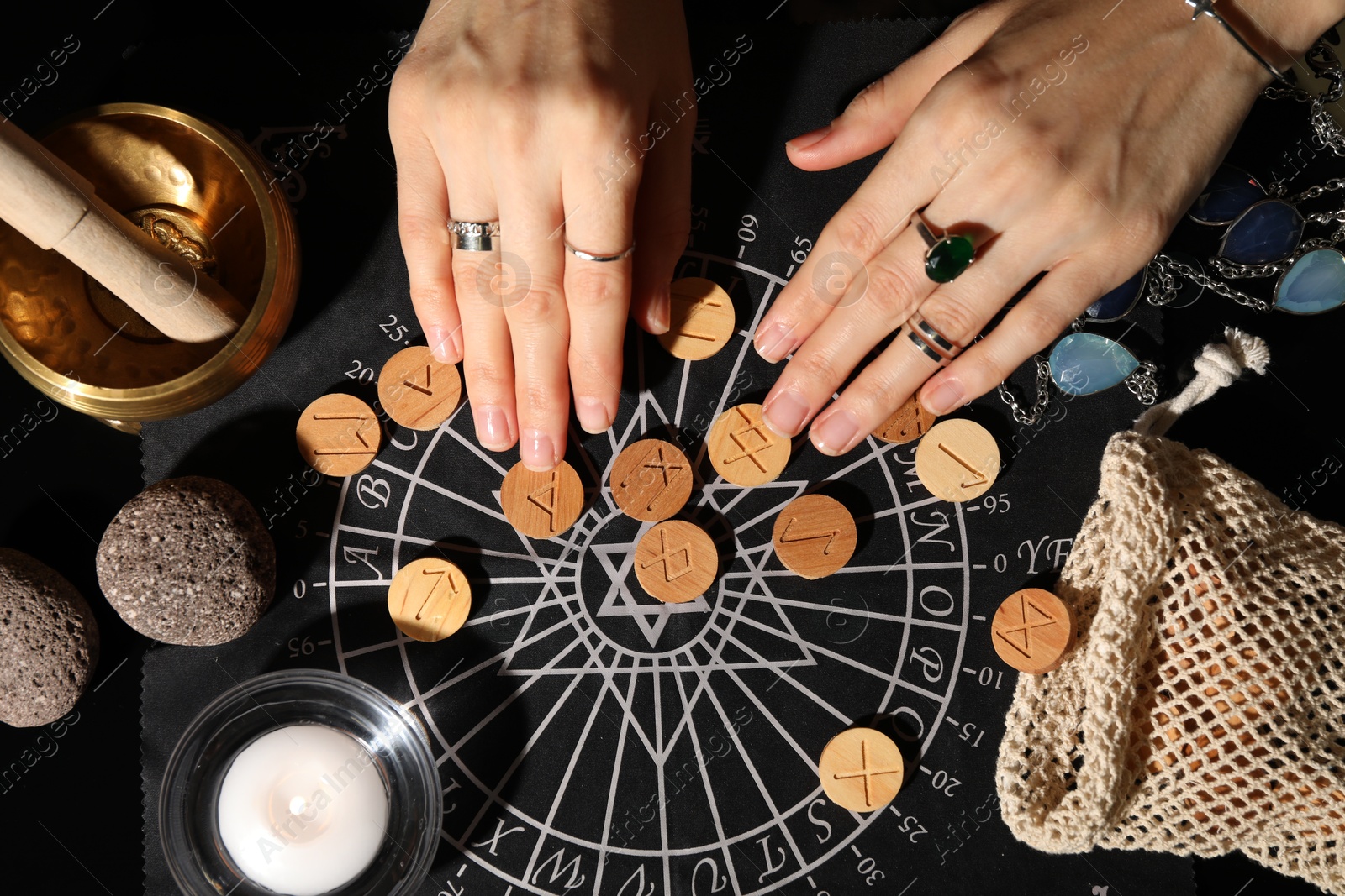 Photo of Woman with wooden runes at divination mat indoors, top view