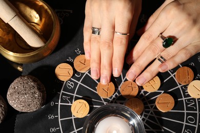 Photo of Woman with wooden runes at divination mat indoors, top view