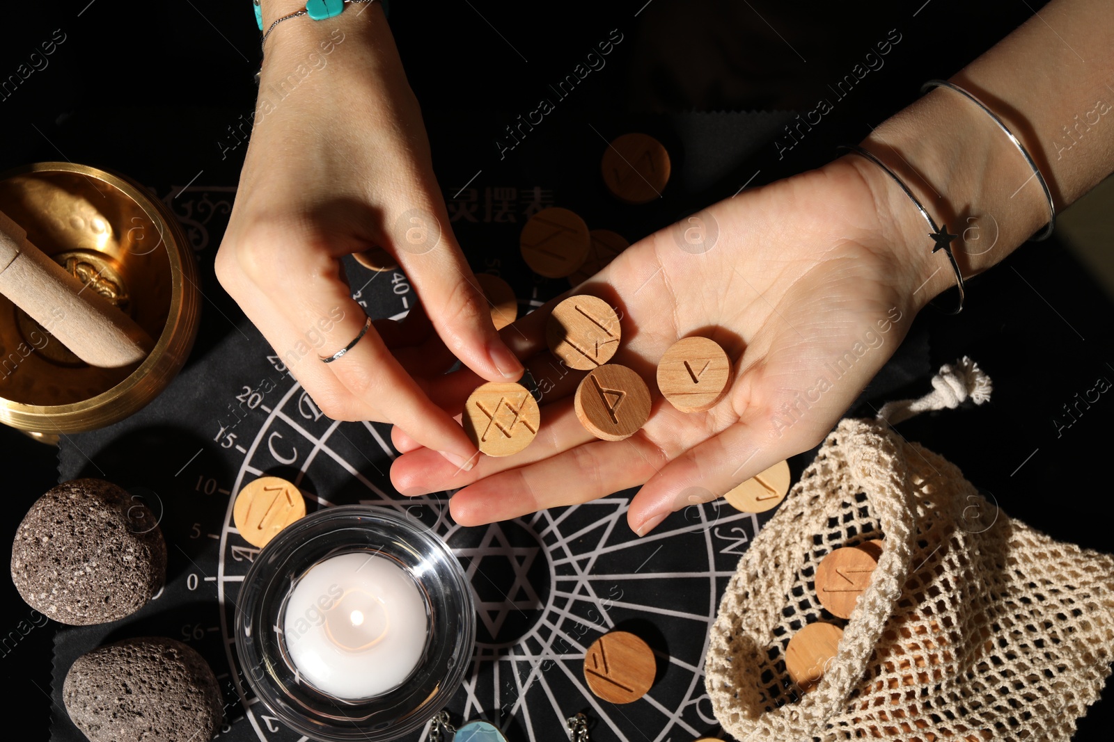 Photo of Woman with wooden runes at divination mat indoors, top view