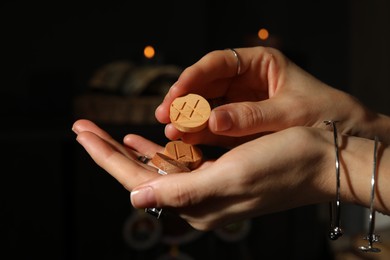 Photo of Woman with wooden runes on dark background, closeup