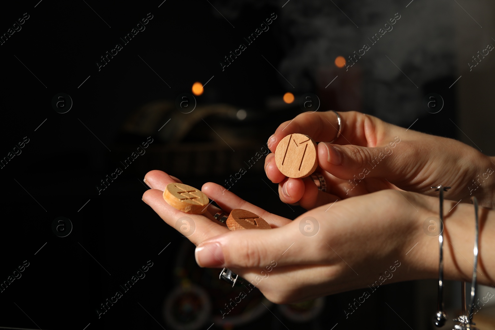 Photo of Woman with wooden runes on dark background, closeup