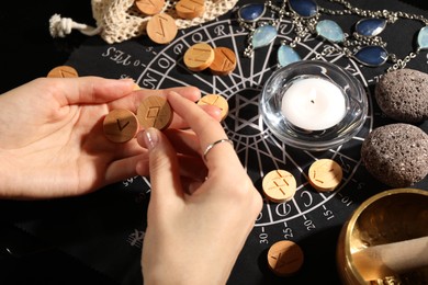 Photo of Woman with wooden runes at divination mat, closeup