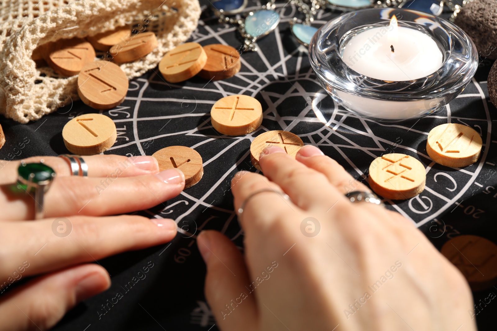 Photo of Woman with wooden runes at divination mat, closeup