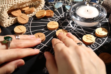 Woman with wooden runes at divination mat, closeup