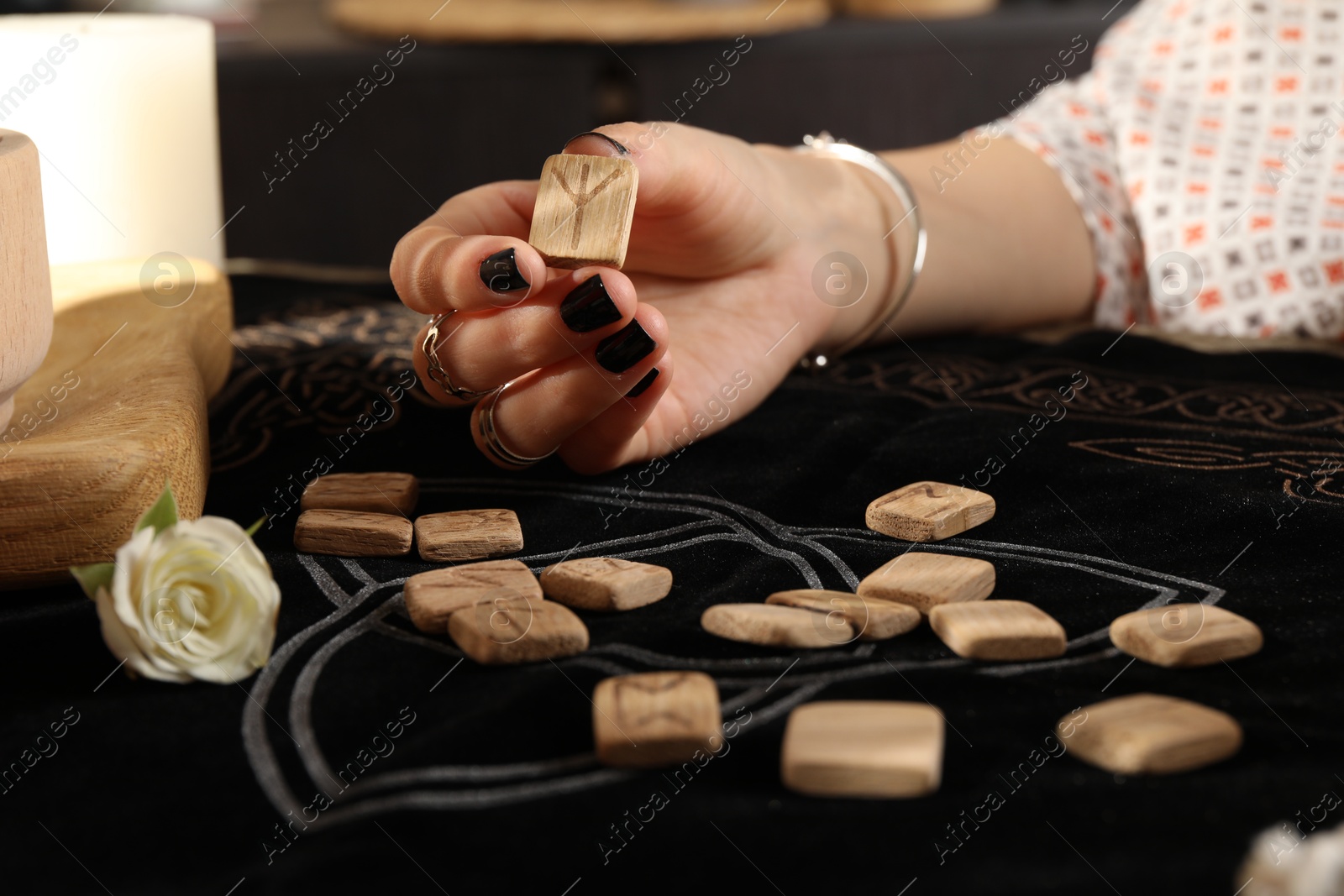 Photo of Woman with wooden rune Algiz at divination mat, closeup