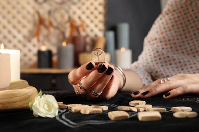 Photo of Woman with wooden rune Algiz at divination mat indoors, closeup